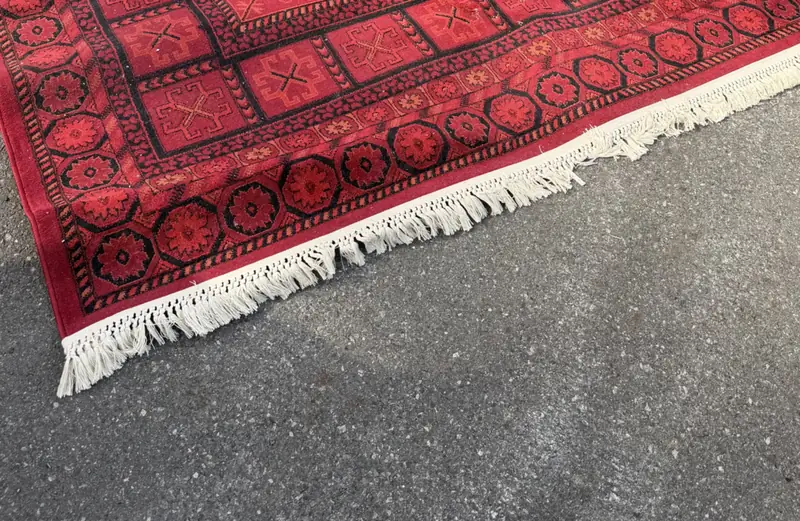 The white fringe along the end of a red rug