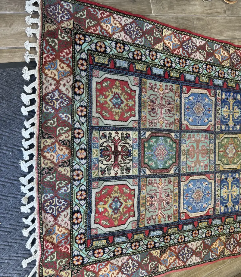 A garden panel rug with knotted fringe laid out flat